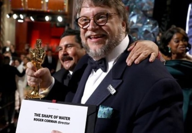 Guillermo Del Toro che mostra il premio Oscar ma il cartellino dice "Roger Corman director"